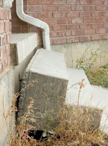 sinking outdoor concrete steps showing cracking and soil washout in Lytle