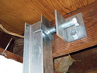 Securing the i-beam system to the top of the floor joist in a foundation wall repair in Kerrville.