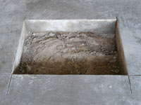 Creating the hole in the garage slab floor during the wall anchor installation in Canyon Lake.