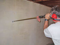 Drilling the hole in the foundation wall for street creep repairs in Gonzales